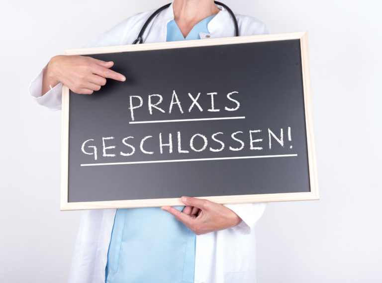 Arzt mit Schild Praxis geschlossen