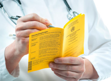International Certificate of Vaccination Der Arzt füllt ein internationales Impfzertifikat aus